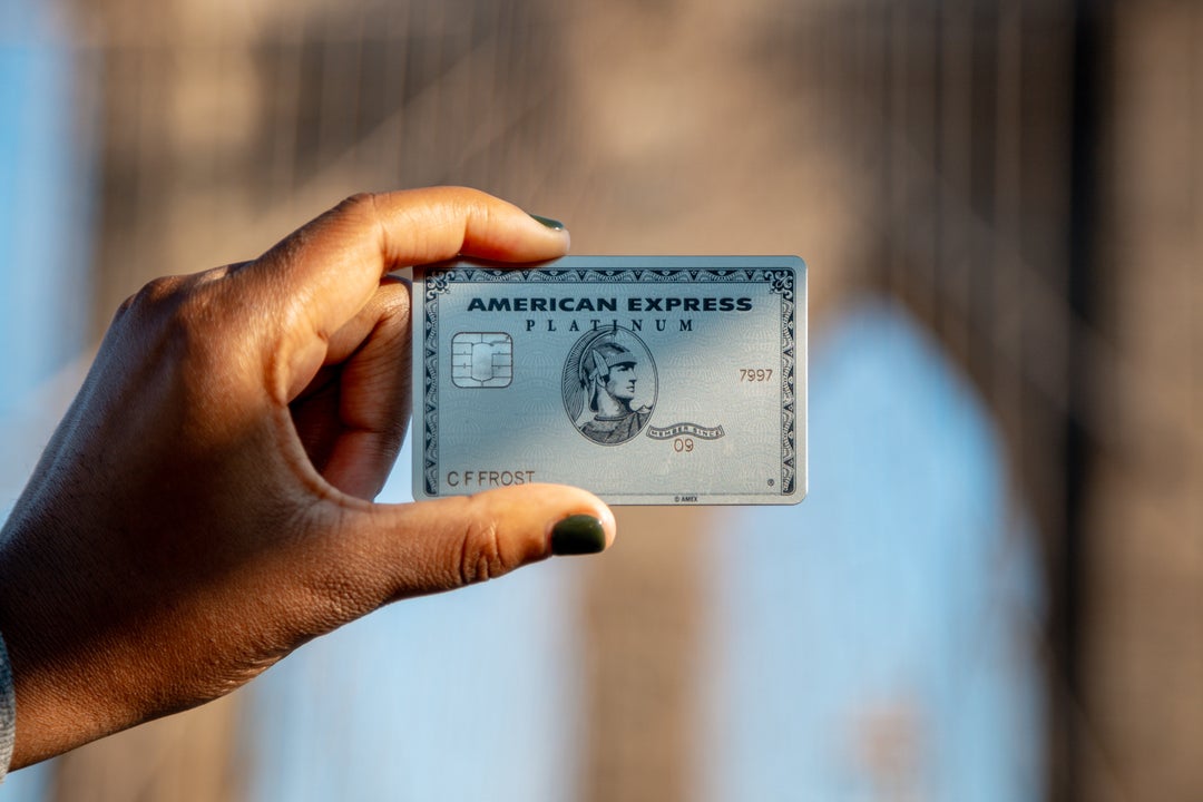 Una mano sostiene una tarjeta American Express Platinum ante un fondo desenfocado