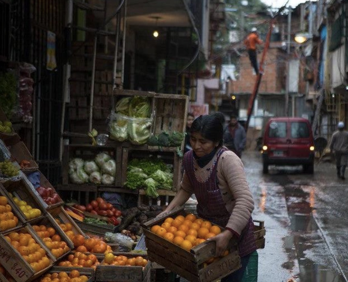Una comerciante organiza cajas de fruta en un puesto de mercado; imagen de contexto facilitada por el editor