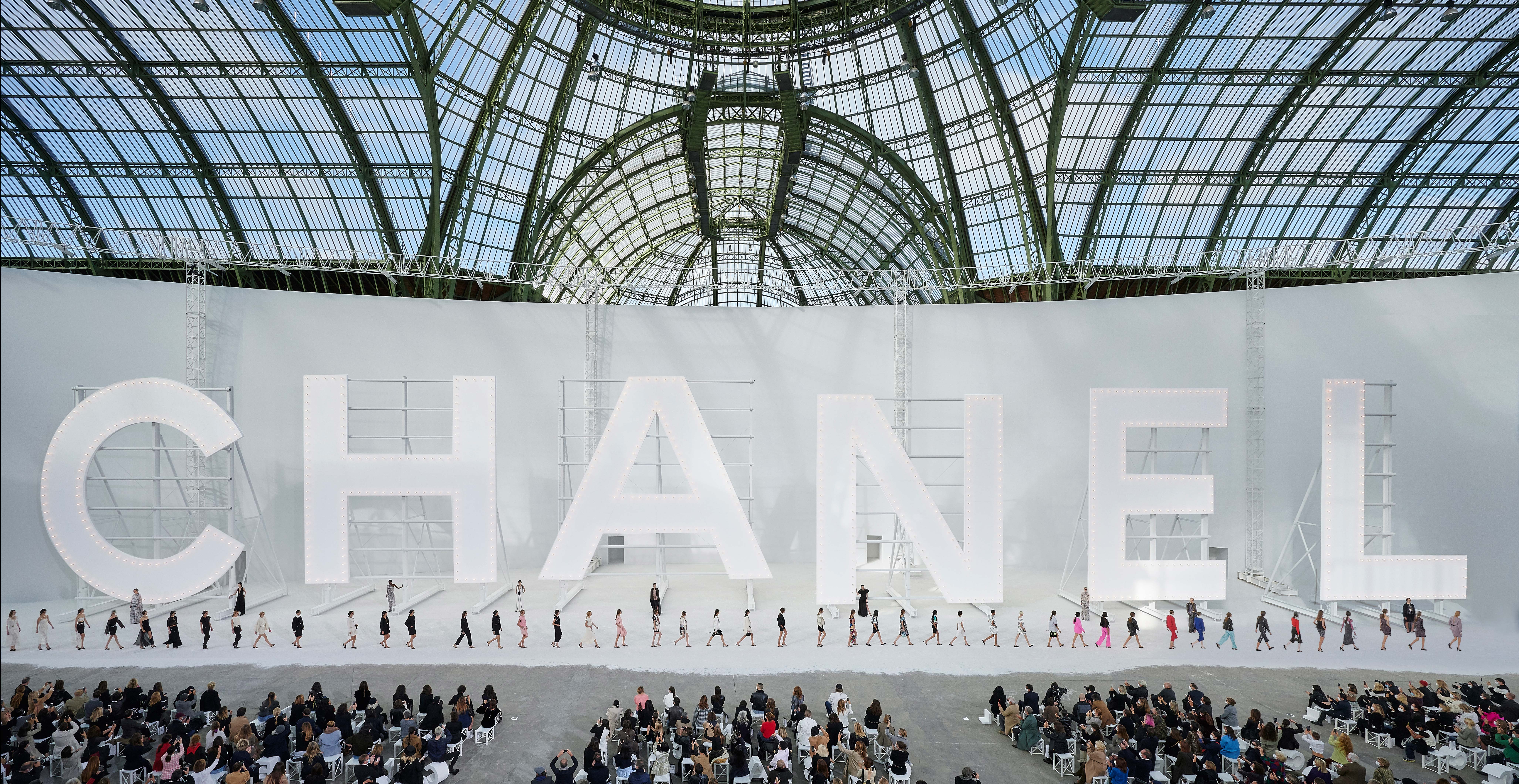 Vista panorámica de un desfile de Chanel en el Grand Palais, con modelos, público y grandes letras de la marca; imagen de archivo