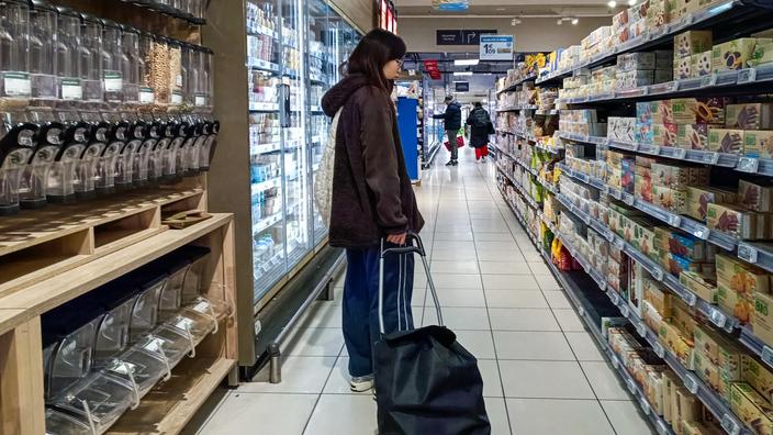 Una compradora con un carro de compra en un pasillo de supermercado
